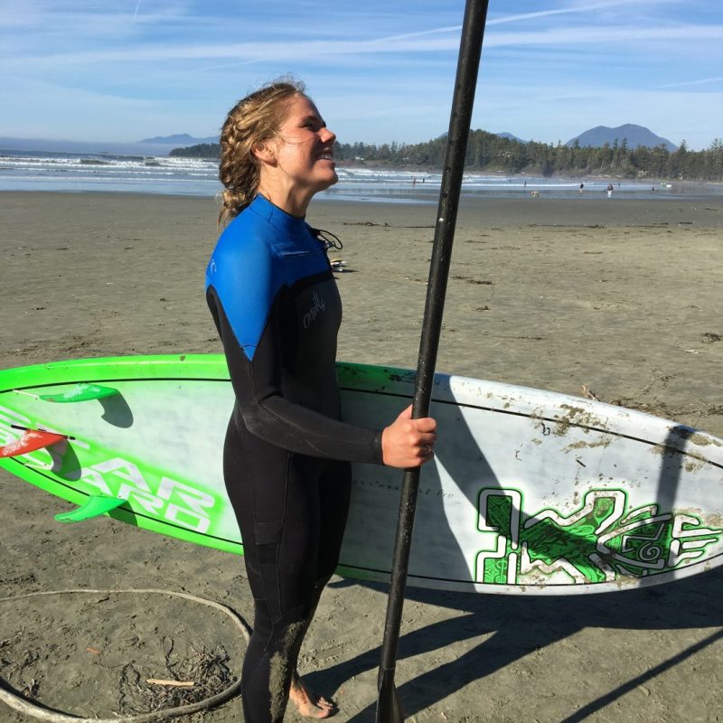 a man standing on top of a sandy beach holding a surf board