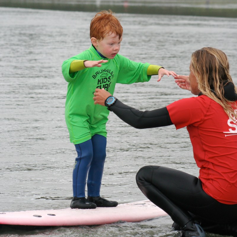 a young boy standing next to a body of water