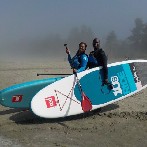a man in a wet suit carrying a surf board on a beach