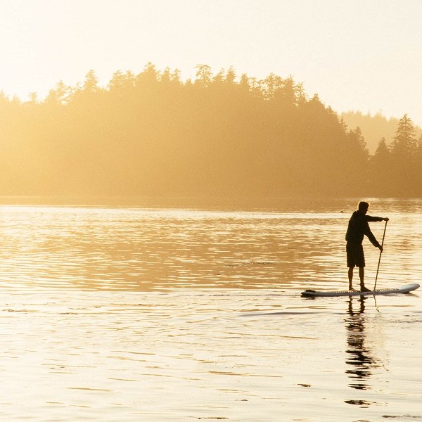 a man walking across a beach next to the water