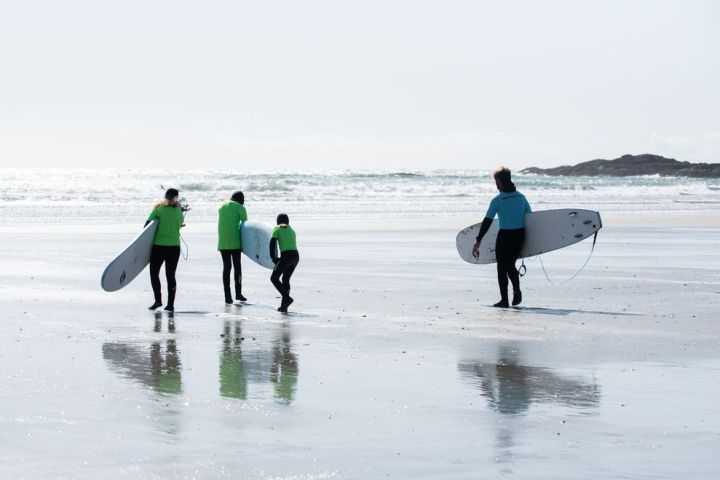 a group of people walking on a beach holding a surfboard