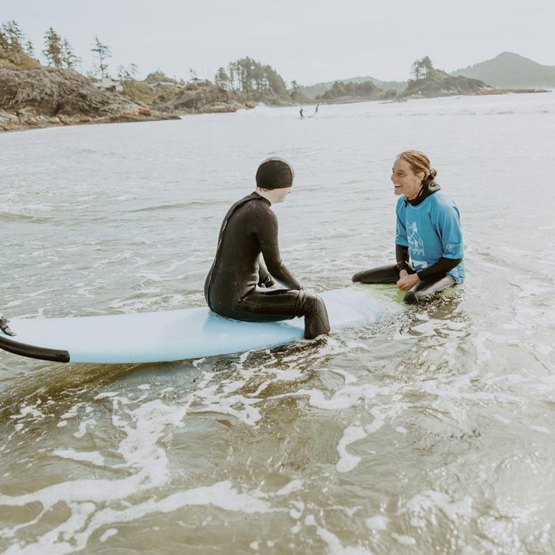 a young boy standing next to a body of water