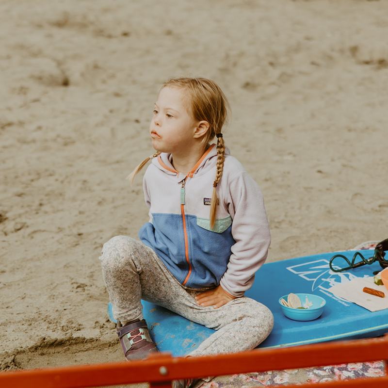 a young boy sitting on a sandy beach