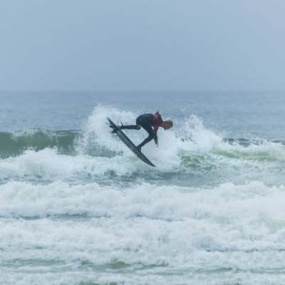 Surfer performing a jump maneuver on a wave.